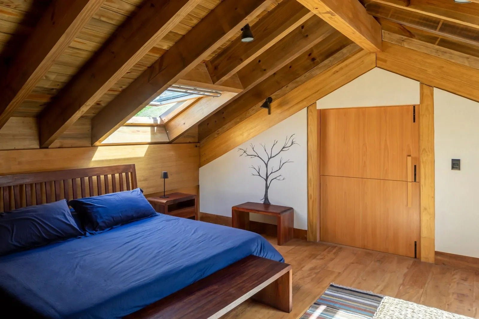Quarto com forro e vigas de madeira aparentes e claraboia